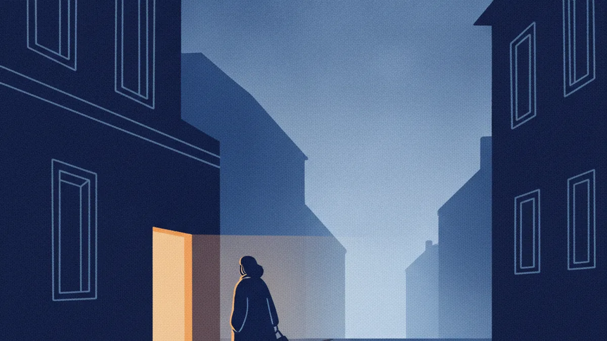 A person walking away from a lit doorway into a quiet blue evening street.