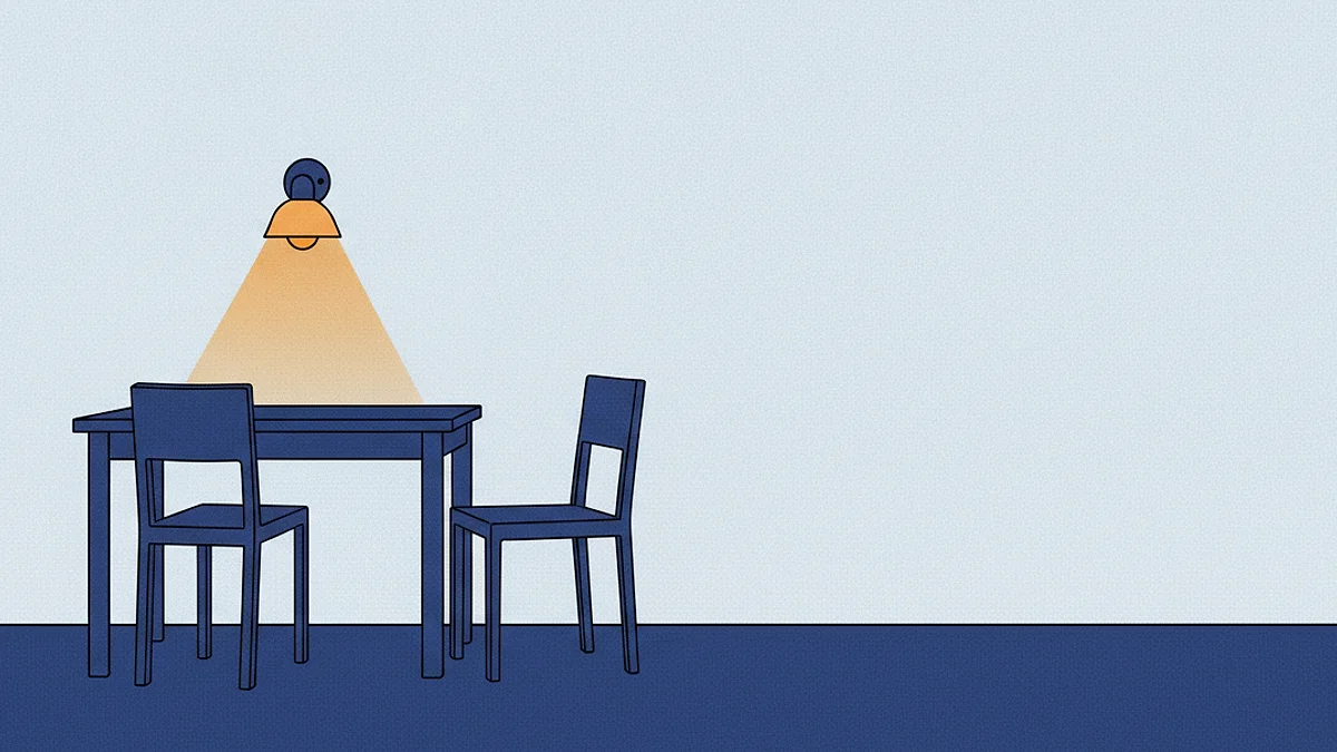 Two chairs at the same small table under one wall lamp: one drawn up to the table, the other standing back from it.